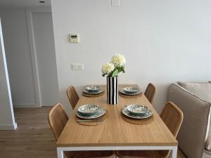 a dining room table with plates and a vase of flowers at Salou SEA SUNSET in Salou