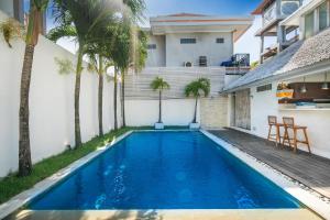 ein Swimmingpool im Hinterhof eines Hauses mit Palmen in der Unterkunft Villa Oberoi in Seminyak + 43 Fotos