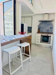 a kitchen with a counter and two white stools at Coral Blue Apartment in Piano di Sorrento