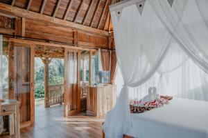 a bedroom with a bed with a white canopy at The Fire Flies Garden Villa in Penginyahan