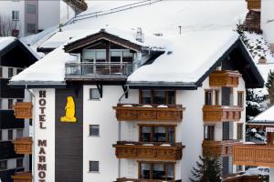 a white building with wooden balconies in the snow at Hotel Marmotte in Saas-Fee