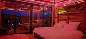 une chambre avec un lit avec des lumières roses dessus dans l'établissement La Luna - Tiny House Spa - Romantique & Nature, à Saint-Yan