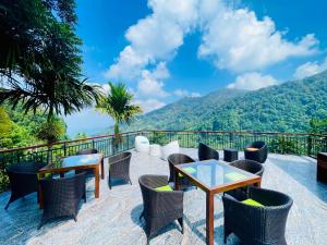 a patio with tables and chairs with mountains in the background at Kavi s Hideaway in Dedugala