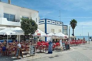 an outdoor restaurant with tables and chairs and the ocean at Apart 2 quartos, 350m praia Olhos d'Água, F in Olhos de Água