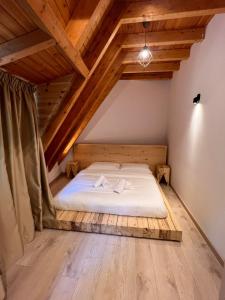 a bed in a room with wooden floors and wooden ceilings at Bujtina Harusha in Theth