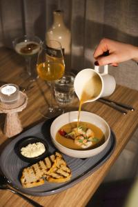 a person is pouring sauce into a bowl of soup at Hótel Vesturland in Borgarnes