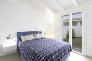 Un dormitorio blanco con una cama azul y una ventana en Blue Sail- Valledoria, en Valledoria