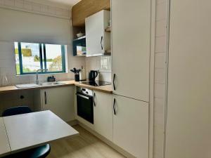 a kitchen with white cabinets and a table and a sink at Azores Pedra Apartments - G in Ponta Delgada +1 photo