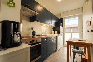 a kitchen with black cabinets and a sink and a table at Superbe appart.55m2 - 200m Ocean et parking in Biscarrosse