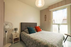 a bedroom with a bed with colorful pillows and a window at Superbe appart.55m2 - 200m Ocean et parking in Biscarrosse
