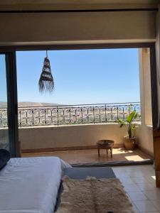 a bedroom with a large window with a view of the ocean at SurfAppart Morocco in Tamraght Ouzdar