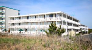 a white building on the beach with chairs and umbrellas at Seabonay Oceanfront Motel in Ocean City
