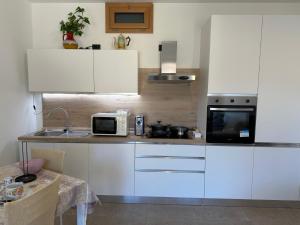a kitchen with white cabinets and a microwave at La Gomonte in Civate