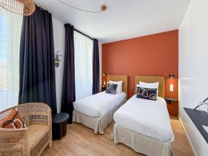 a hotel room with two beds and a chair at Hôtel du Commerce in Cluny