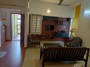 a living room with a table and chairs and a kitchen at 4 Bedroom Service Apartment with Kitchen near Velachery - Madipakkam - Pallikaranai in Chennai