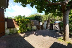 a brick driveway with a fence and a tree at Maisonnette au pied de l'Océan avec terrasse in Biscarrosse +22 photos