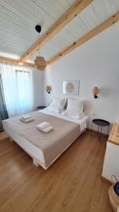a bedroom with a large white bed with wooden floors at Tonea's Houses in Himare