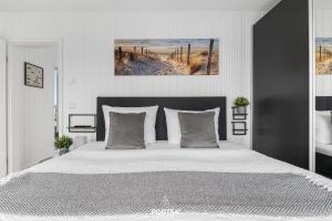 a white bedroom with a large white bed with pillows at Ferienhaus Am Pier Olpenitz in Olpenitz