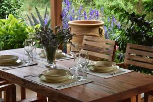 a wooden table with plates and glasses and flowers on it at Sycamore House in Skiathos Town