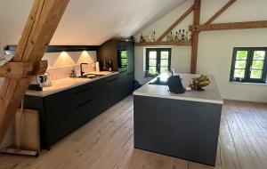 a large kitchen with black cabinets and a wooden floor at Buchmühle in Niederdorla +20 photos