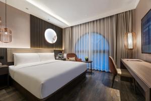 um quarto de hotel com uma cama grande e uma escrivaninha em 杭州西湖桔子水晶酒店 em Hangzhou