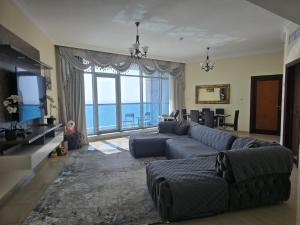a living room with a couch and a large window at Sunset Ajman Beach - kids friendly in Ajman 