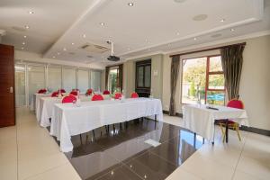 a meeting room with white tables and red chairs at Tamboti Guest Lodge in Pretoria +148 photos
