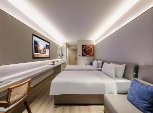 a hotel room with two beds and a couch at 杭州运河万达广场桔子水晶酒店 in Hangzhou