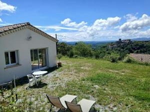 un groupe de chaises et une table dans une cour dans l'établissement Gîte Les Mimosas - 2 à 4 personnes - Vue imprenable, à Largentière