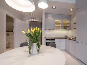 a white kitchen with a vase of yellow flowers on a table at Apartament z widokiem na dworek in Gdańsk