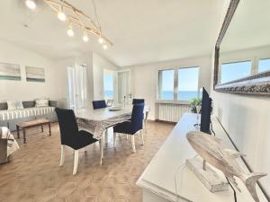 Un comedor y una sala de estar con mesa y sillas. en Rosanna, terrazza vista mare, 2 camere, clima e 2 posti auto a soli 50 m dal mare! by Alfareal, en Castiglione della Pescaia