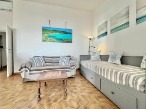 un dormitorio con dos camas y un sofá en Rosanna, terrazza vista mare, 2 camere, clima e 2 posti auto a soli 50 m dal mare! by Alfareal, en Castiglione della Pescaia