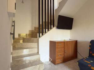 a room with a staircase with a tv and a wooden cabinet at Domus Vespro in Villasimius