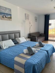1 Schlafzimmer mit 2 Betten mit blauer Bettwäsche und einem Sofa in der Unterkunft Blue Ocean in Costa Del Silencio