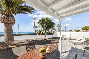 Un patio con mesa y sillas y una palmera. en Casahost El Cable Seaview Beach house, en Arrecife