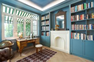 a library with blue walls and a desk and a mirror at Éclectique Hanoi Homestay in Hanoi