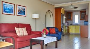 a living room with a red couch and blue chairs at Balcon de Jandia Ático Penthouse in Morro del Jable