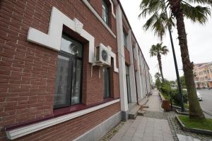 a red brick building with a window and a sidewalk at Poti Seaside Apartment in Poti