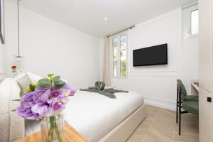 a living room with a vase of purple flowers on a table at SUITE DELUXE - MONACO - Vue Jardin in Beausoleil