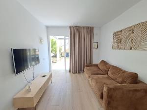 a living room with a couch and a flat screen tv at Apartamentos Alisios con terraza y piscina in Corralejo