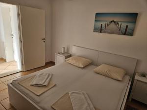 a white bed with two towels on top of it at Apartments KraljicaMira in Splitska +50 photos