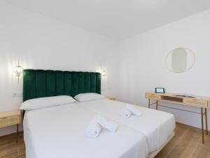a bedroom with a large white bed with a green headboard at Alisios Easy Stay in Corralejo +18 photos