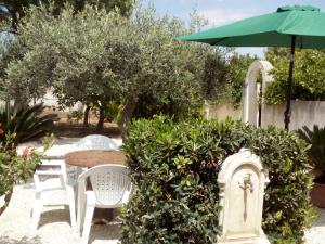 a garden with a table and chairs and an umbrella at Monolocale Birgi in Birgi Vecchi