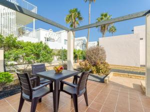 a table and chairs on a patio with palm trees at Alisios Easy Stay in Corralejo