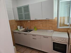 a kitchen with white cabinets and a sink and a window at Apartments KraljicaMira in Splitska