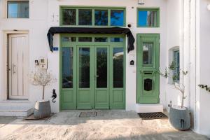 a green door on a white building with windows at Sophisticated Paros Getaway in Parikia