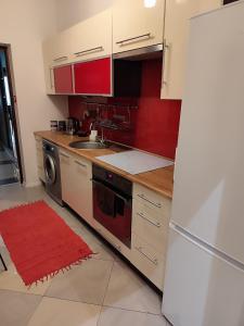 a kitchen with red cabinets and a sink and a refrigerator at Apartament Karolek in Przemyśl +5 photos