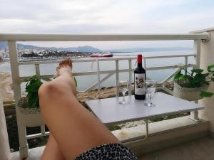a person with their feet on a table with a bottle of wine at Little gem in Rafina +10 photos