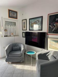 a living room with two chairs and a flat screen tv at Little Beachouse Prvic Island in Prvić Šepurine