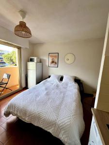 a bedroom with a white bed and a refrigerator at Studio proche plage et centre-ville in Sainte-Maxime